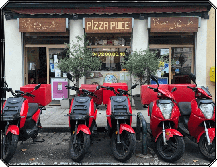 Scooters électriques garés devant la devanture du restaurant PIZZA PUCE Lyon