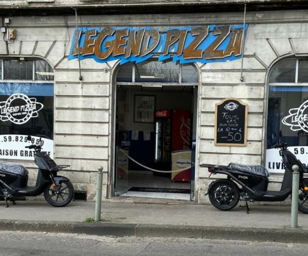 Scooters électriques garés devant le restaurant à pizzas LEGEND PIZZA