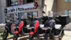 Scooters électriques garés devant le restaurant Boite à pizza