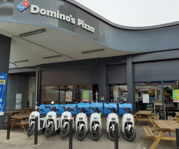 Scooters électriques blanc garés devant Dominos Pizza Roanne