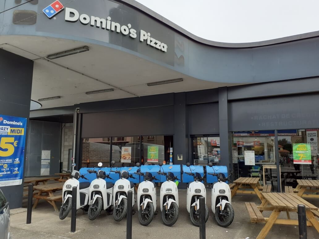 Scooters électriques blanc garés devant Dominos Pizza Roanne