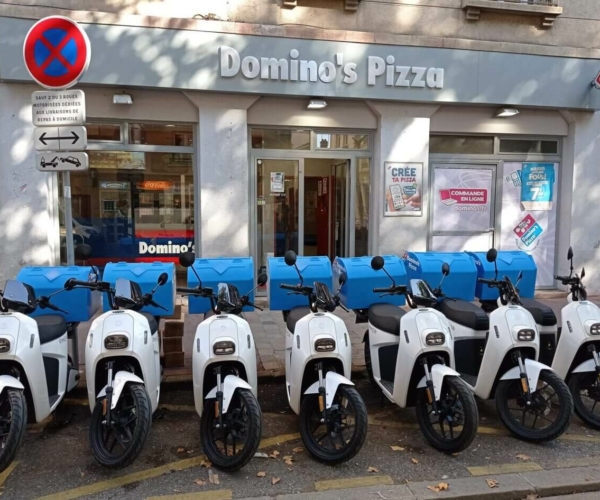 Scooters électriques blancs garés devant le restaurant Domino's Pizza LYON