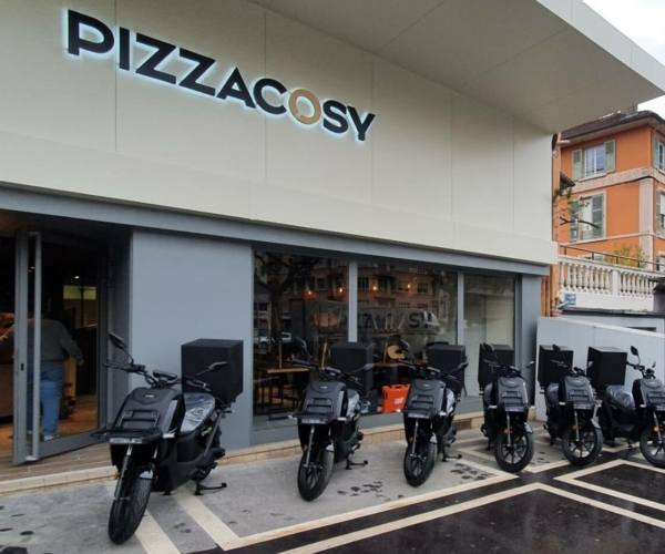 Scooters électriques noirs garés devant le restaurant Pizza Cosy