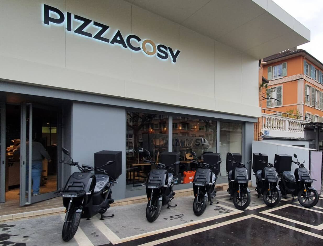 Scooters électriques noirs garés devant le restaurant Pizza Cosy