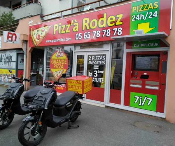 Deux scooters électriques noirs garés devant un restaurant à RODEZ