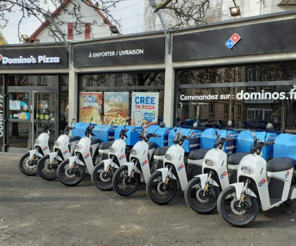 Scooters électriques garé devant Domino's Pizza