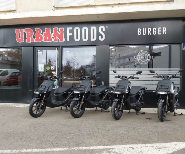 Quatre scooters électriques garés devant URBAN FOOD